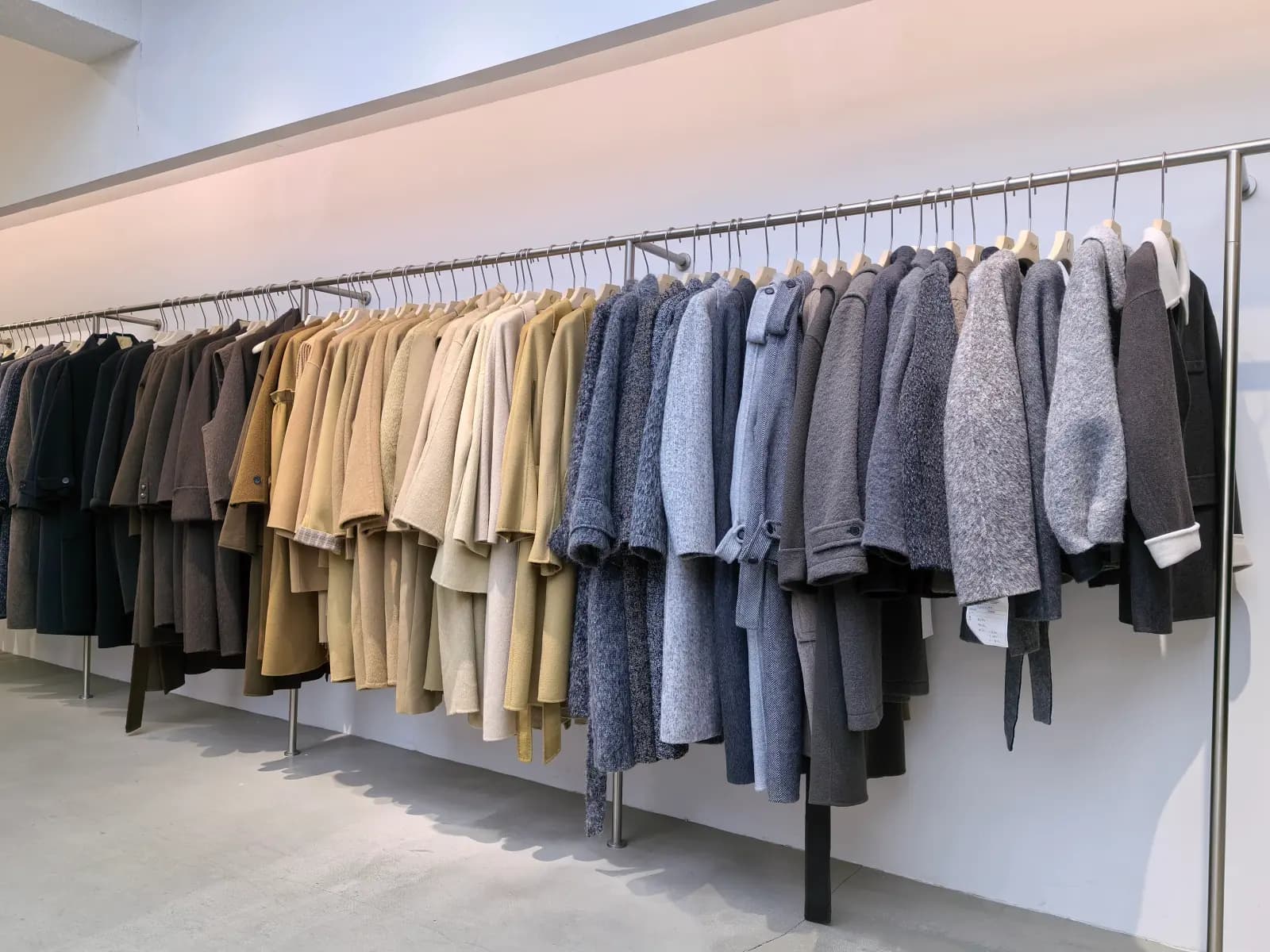 A showroom rail displaying selected wool and cashmere coats in neutral tones