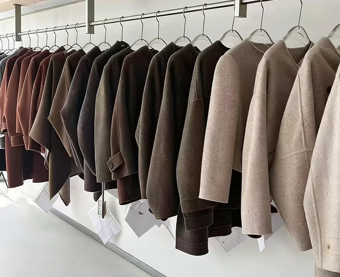 A showroom rail displaying selected wool and cashmere coats in neutral tones