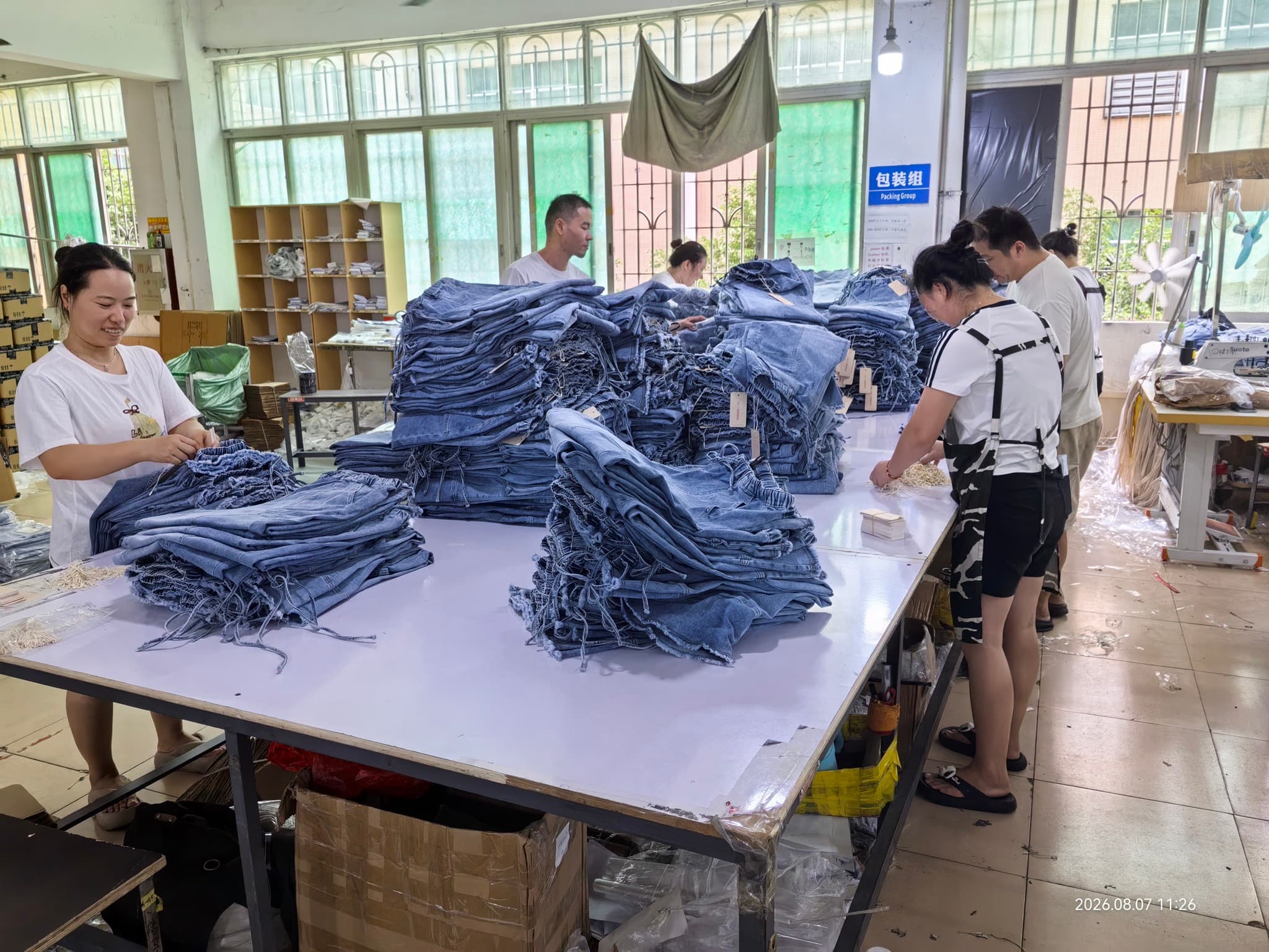 Workers sorting and packing denim garments at a production table